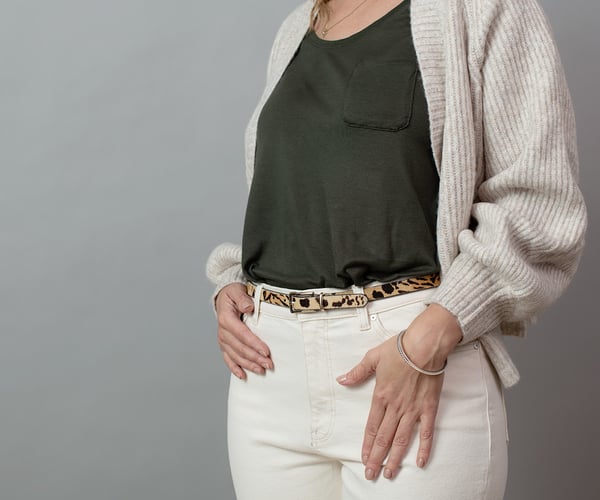 Frau mit grünem Oberteil und weißer Hose; ThermaCare® Wäremeauflage bei Regelschmerzen ist nicht zu sehen