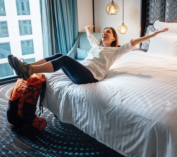 Frau springt auf ein Hotelbett