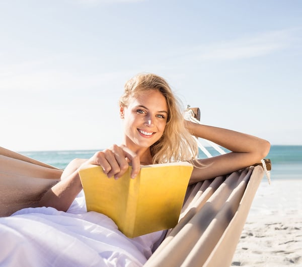 Eine Frau liest ein Buch am Strand 