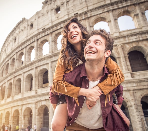 Ein Mann trägt eine Frau auf dem Rücken und sie stehen vor dem Kolosseum in Rom