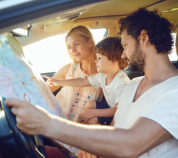 Eine Familie unterwegs im PKW schaut gemeinsam auf eine Landkarte