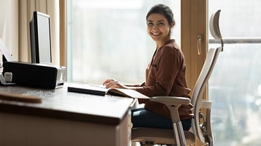 Eine Frau sitzt an ihrem ergonomisch ausgerichteten Schreibtisch